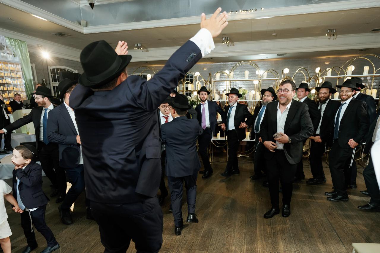 Raised arms and lively expressions fill a close dance-floor photograph. Bar Mitzvah photography at Eagle Ridge, Lakewood, NJ.