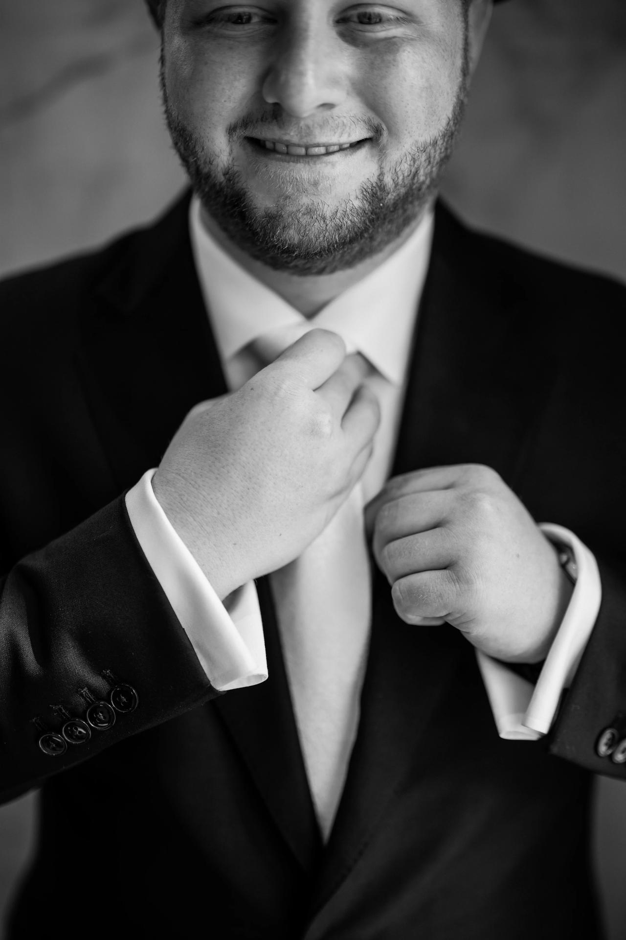 A tight black-and-white detail of the groom’s bow tie and cuff adjustment. Wedding photography at Ateres Charna, New Square, NY.