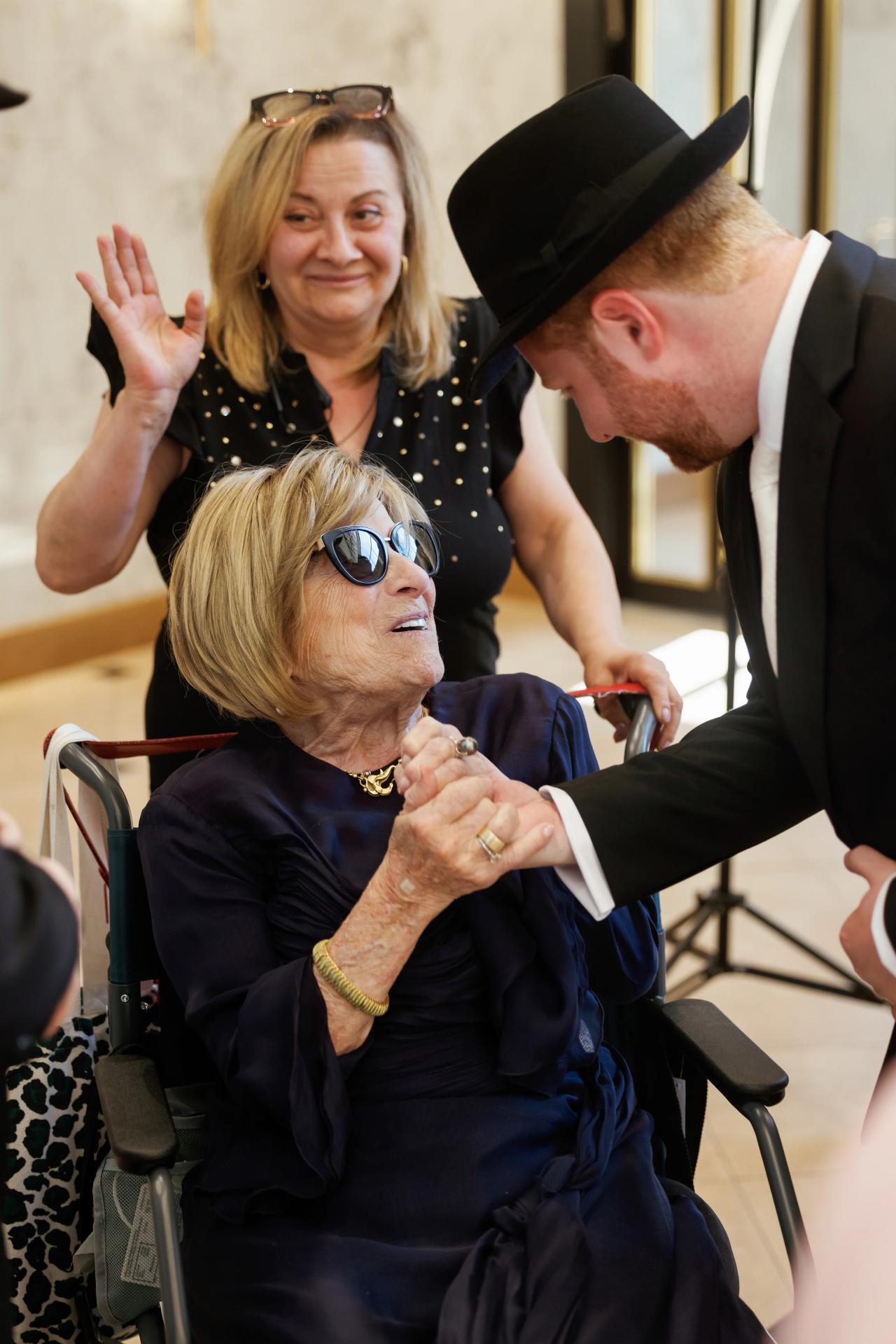 A close black-and-white detail of clasped hands spanning generations. Wedding photography at Ateres Charna, New Square, NY.
