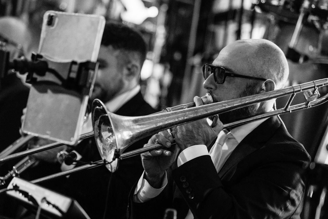 A black-and-white detail of a trumpet player performing with the wedding band. Wedding photography at Ateres Charna, New Square, NY.