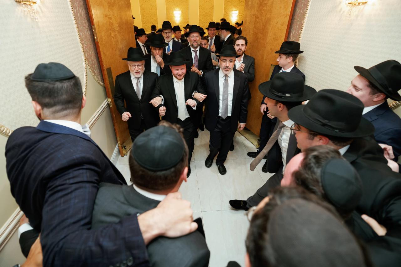 The groom entering through a singing crowd in warm gold light. Wedding photography at Ateres Charna, New Square, NY.