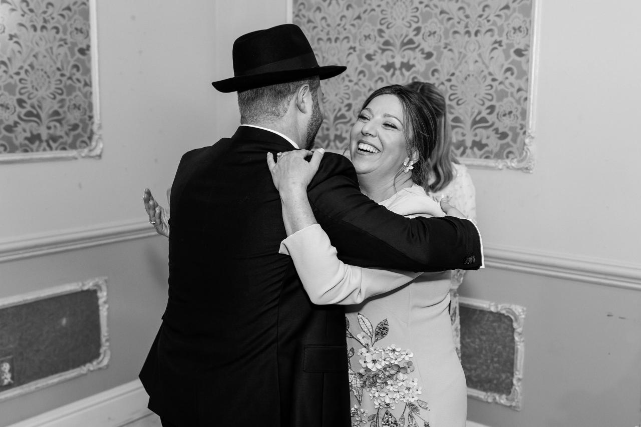 A close black-and-white family embrace before the wedding ceremony. Wedding photography at Ateres Charna, New Square, NY.