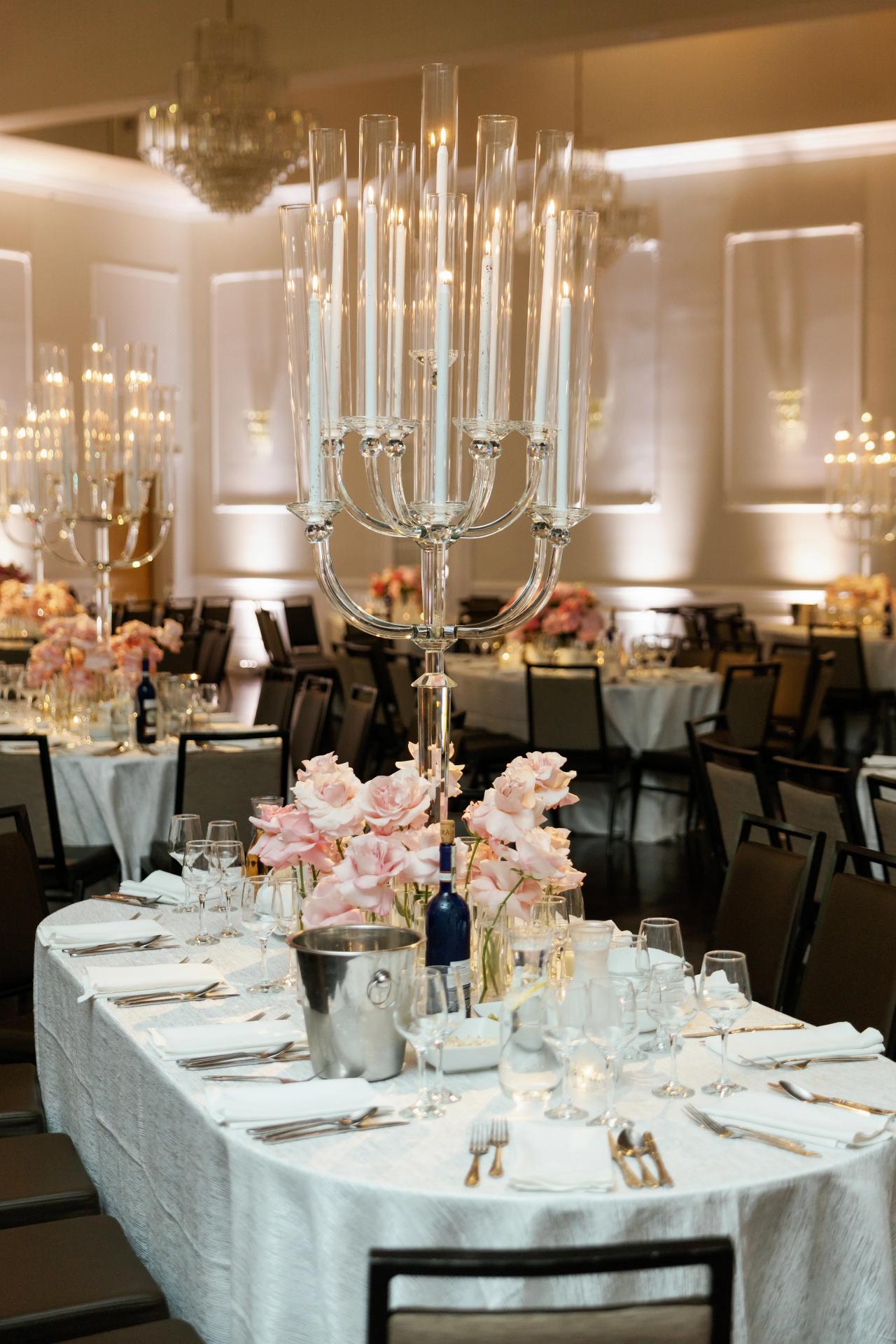 A wide view of the Ateres Charna reception ballroom, with candlelit tables and tall windows. Wedding photography.