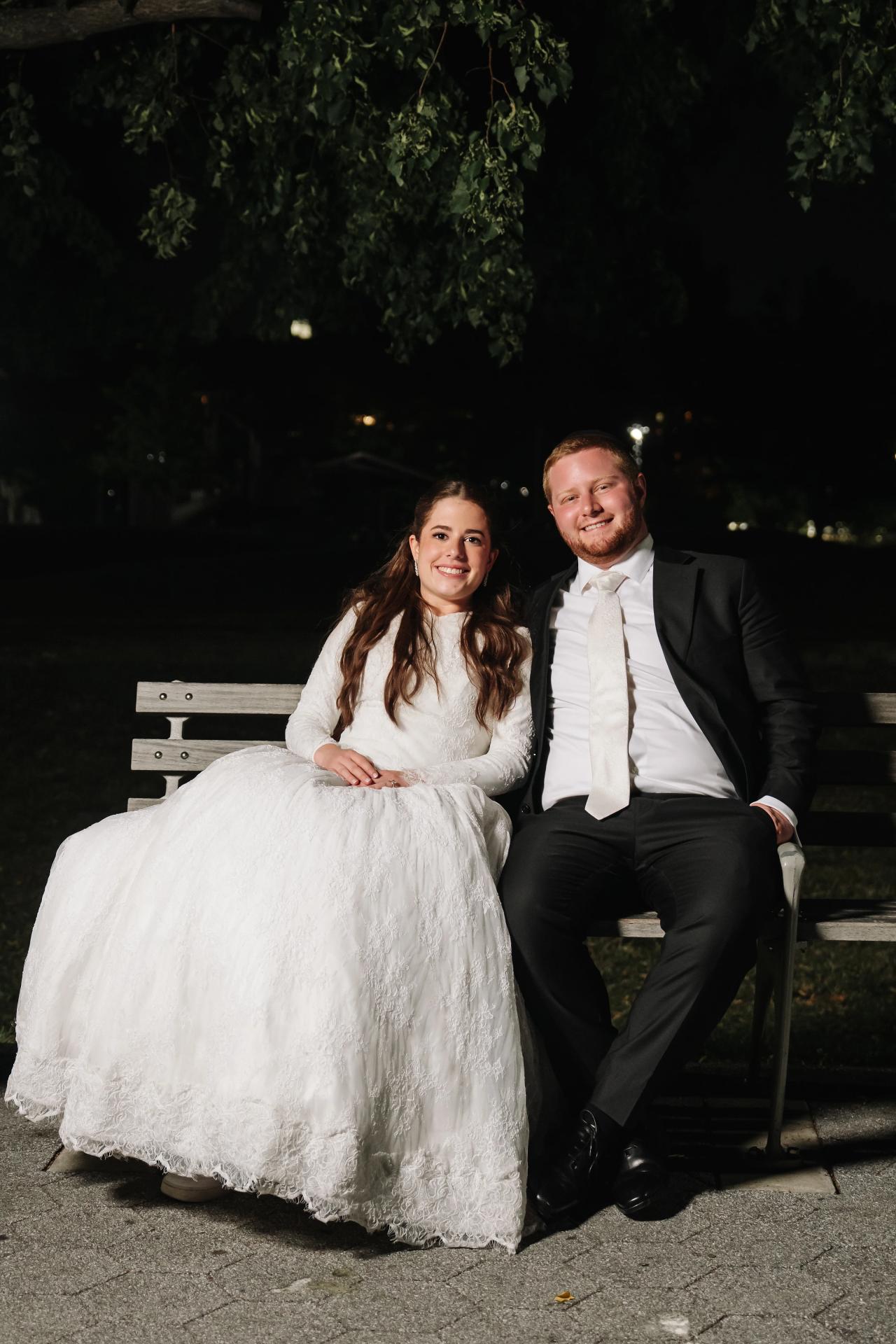 The newlyweds seated outdoors together in a relaxed night portrait, from the Ateres Charna wedding portrait collection. Wedding photography.