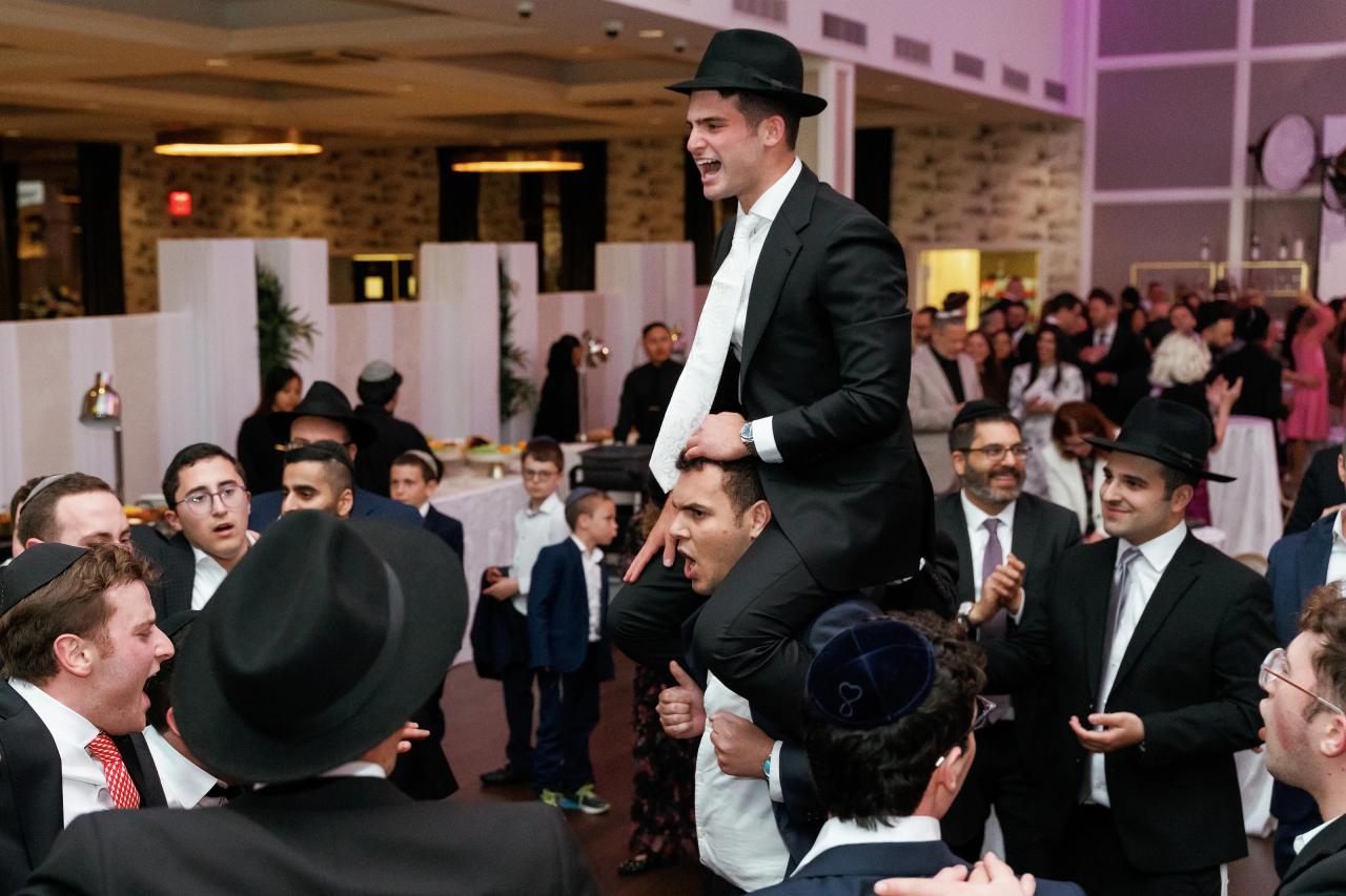 The groom lifted above his celebrating friends. Wedding photography at Brightstone, Passaic, NJ.