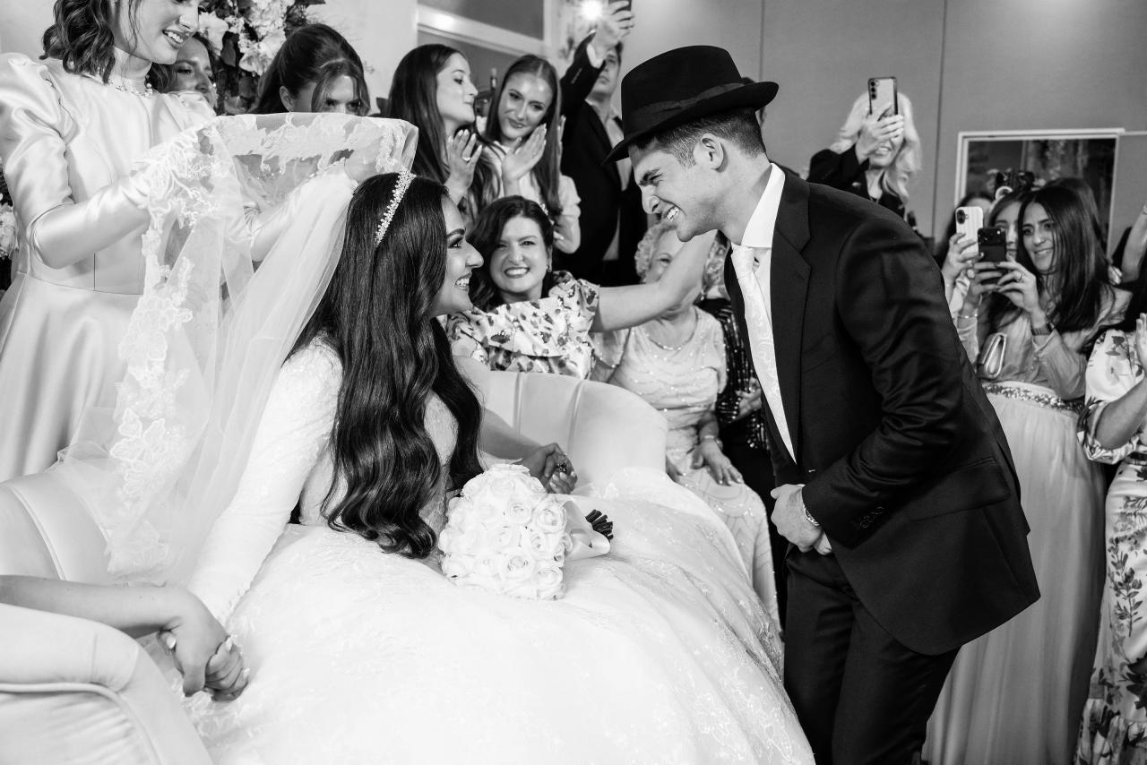 A tender black-and-white kiss with the veiled bride at the bedeken. Wedding photography at Brightstone, Passaic, NJ.