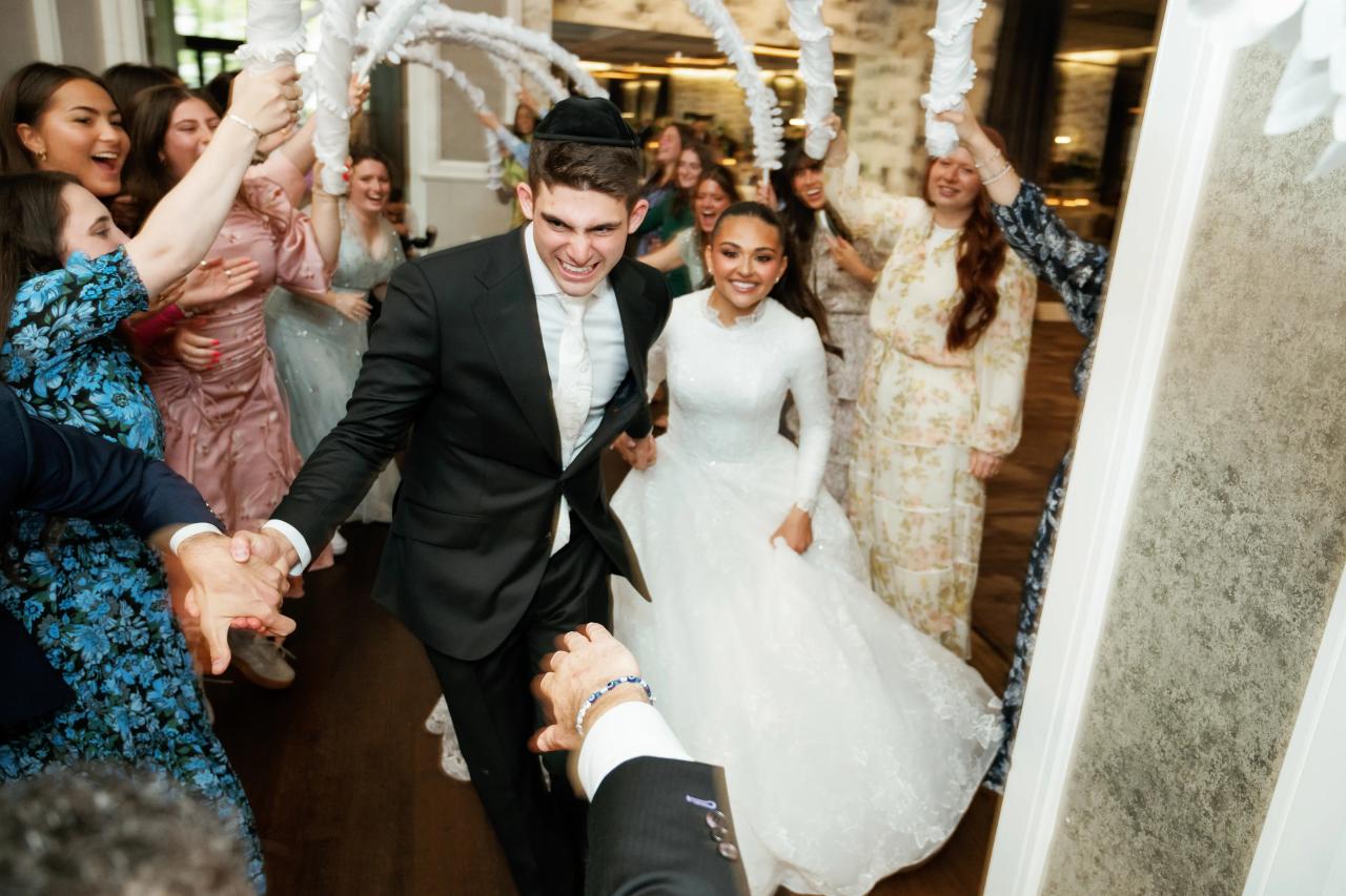 The couple enters the reception beneath a tunnel of raised celebration props. Wedding photography at Brightstone, Passaic, NJ.
