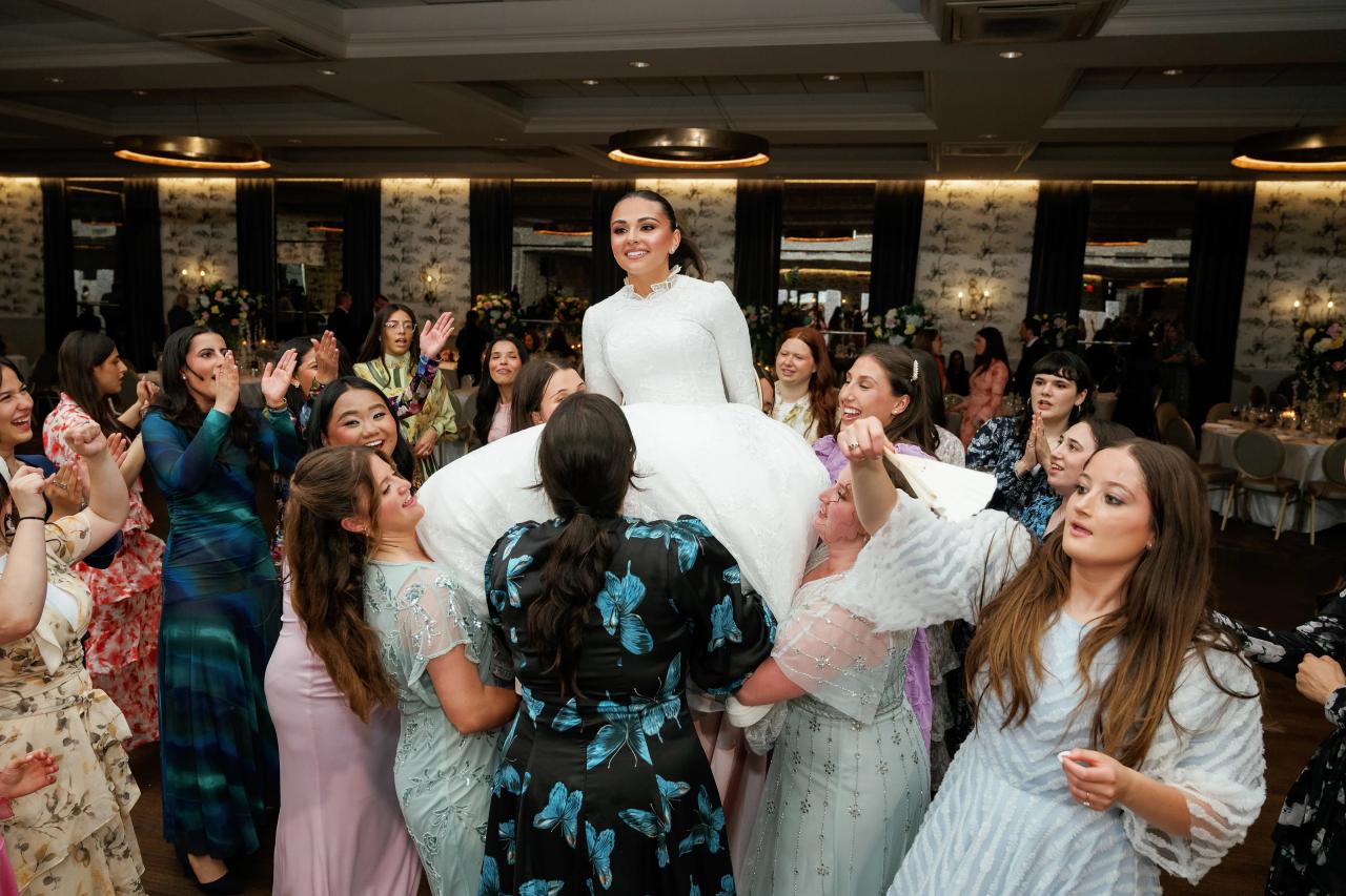The bride lifted above a circle of cheering women. Wedding photography at Brightstone, Passaic, NJ.