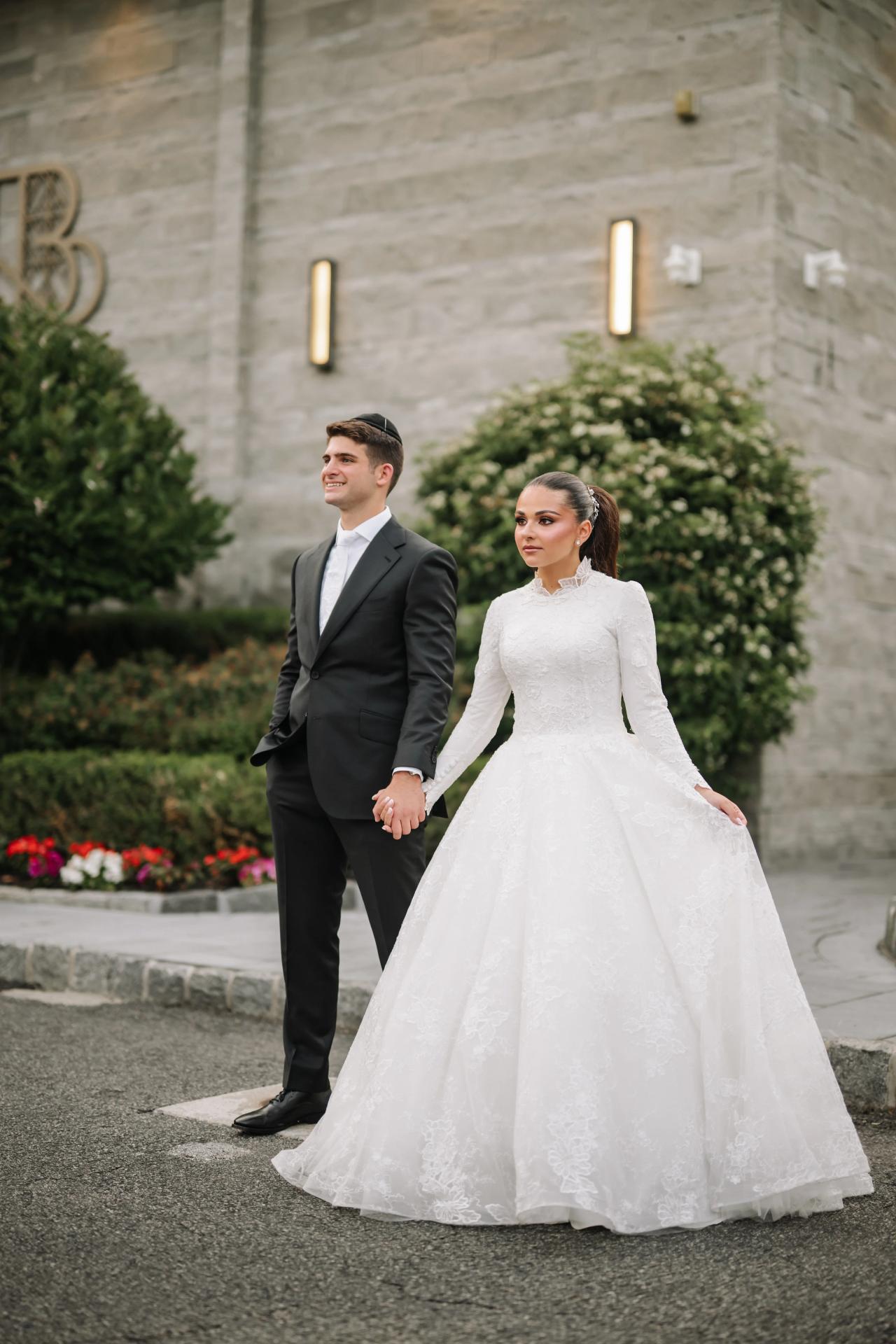 The bride and groom framed by entrance architecture and a flowing wedding gown. Wedding photography at Brightstone, Passaic, NJ.