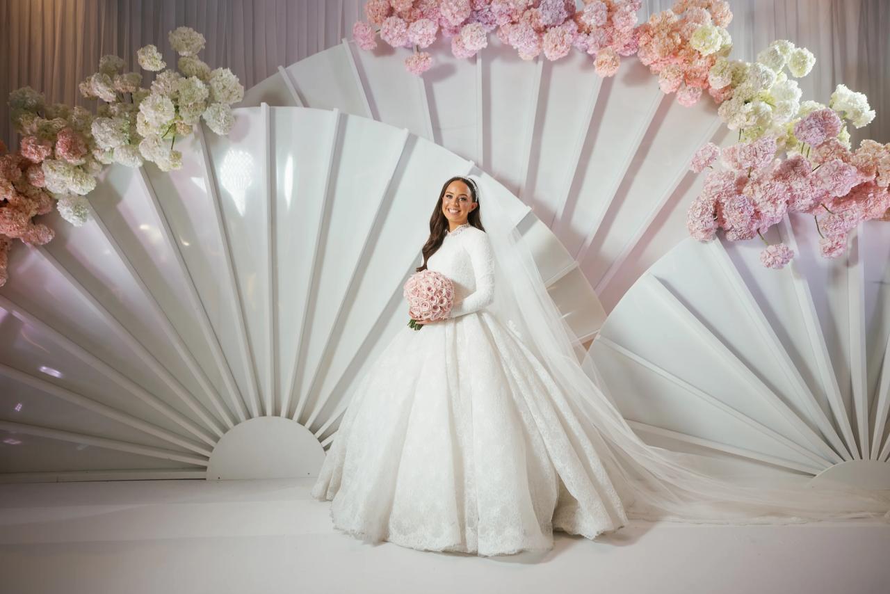 Bride framed by sculptural white fan-shaped decor and pale pink flowers. Wedding photography at Hilton Baltimore Inner Harbor, Baltimore, MD.