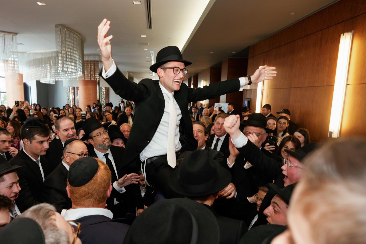 Groom lifted by friends with arms wide during the bedeken gathering; expressive joy. Wedding photography at Hilton Baltimore Inner Harbor, Baltimore, MD.
