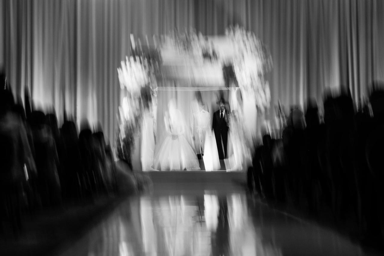 Intentional black-and-white motion blur across the floral chuppah and reflective aisle. Wedding photography at Hilton Baltimore Inner Harbor, Baltimore, MD.