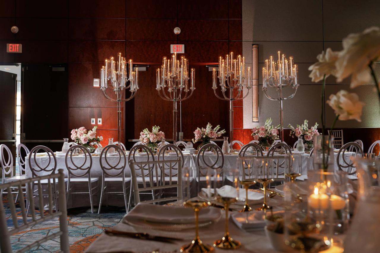 Candlelit reception table with tall candelabras, pale flowers, and repeating circular chair backs. Wedding photography at Hilton Baltimore Inner Harbor, Baltimore, MD.