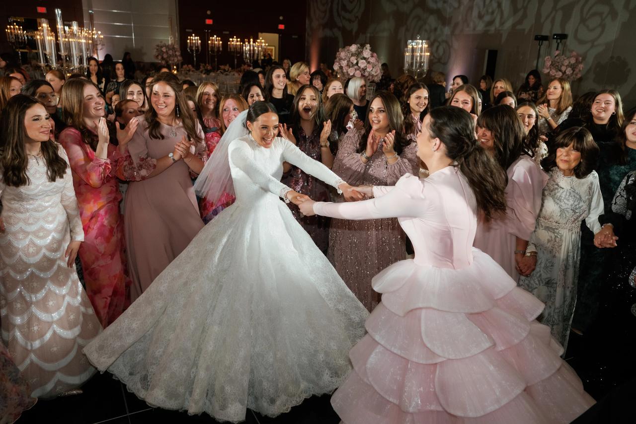 Bride spinning with a guest, her full skirt in motion amid smiling friends. Wedding photography at Hilton Baltimore Inner Harbor, Baltimore, MD.