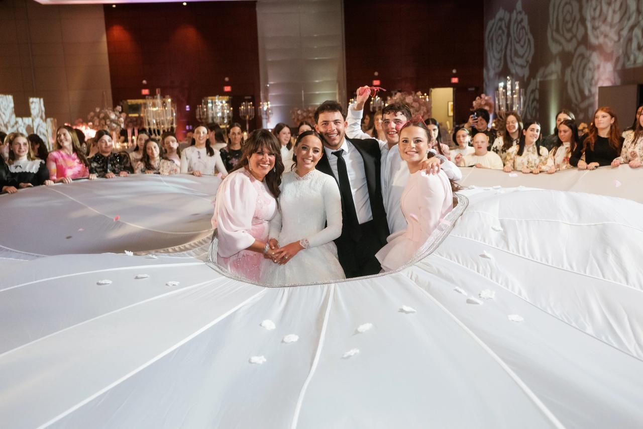 Bride with family in the center of a wide white parachute; unusual radial composition. Wedding photography at Hilton Baltimore Inner Harbor, Baltimore, MD.