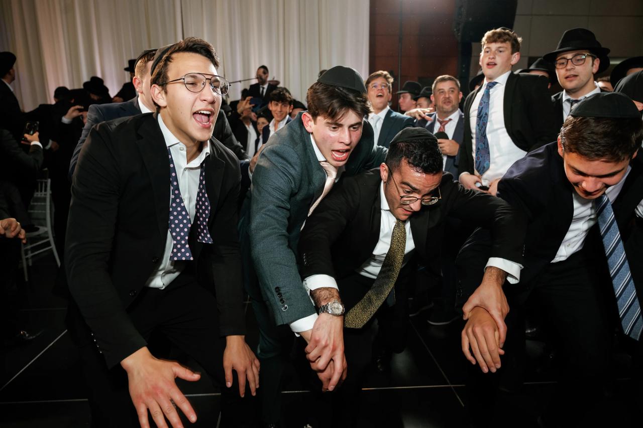 Friends leaning forward together and cheering on the dance floor. Wedding photography at Hilton Baltimore Inner Harbor, Baltimore, MD.