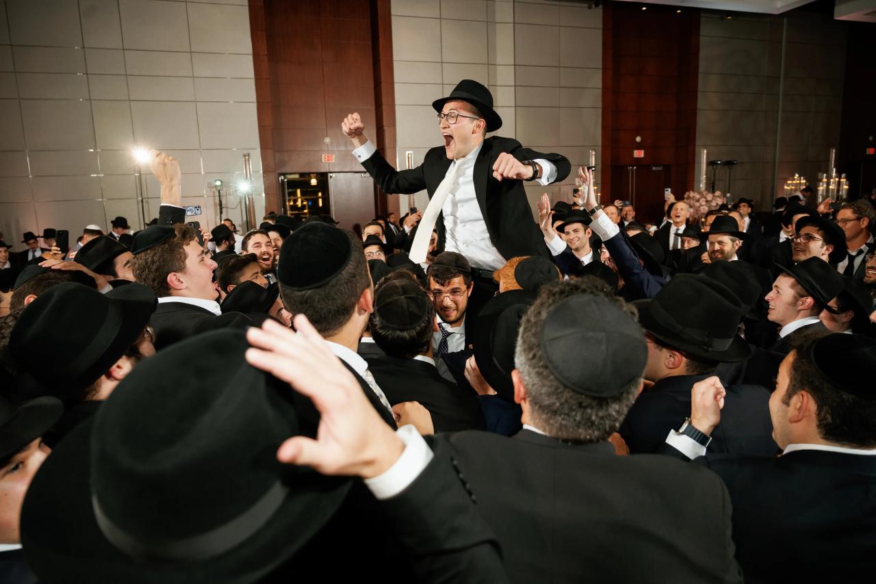 Groom raised above the crowd with fists lifted and friends singing around him. Wedding photography at Hilton Baltimore Inner Harbor, Baltimore, MD.