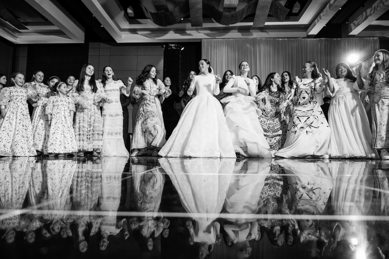 Wide black-and-white women’s dance circle with striking reflections in the glossy floor. Wedding photography at Hilton Baltimore Inner Harbor, Baltimore, MD.