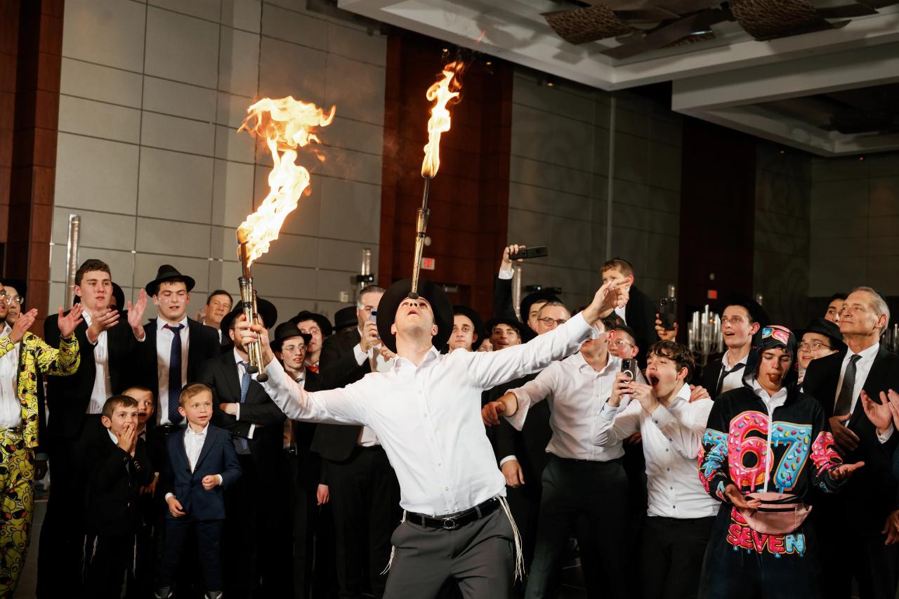 Flaming torches in midair above a performer, surrounded by guests reacting. Wedding photography at Hilton Baltimore Inner Harbor, Baltimore, MD.