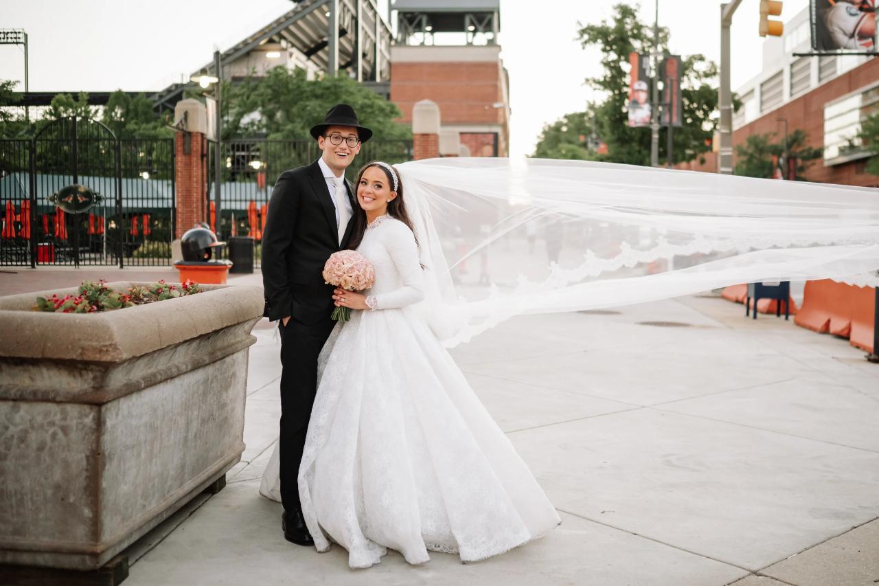 Couple outside near Camden Yards with the veil stretched horizontally across the frame — couple portraits for the Hilton Baltimore Inner Harbor wedding. Wedding photography.