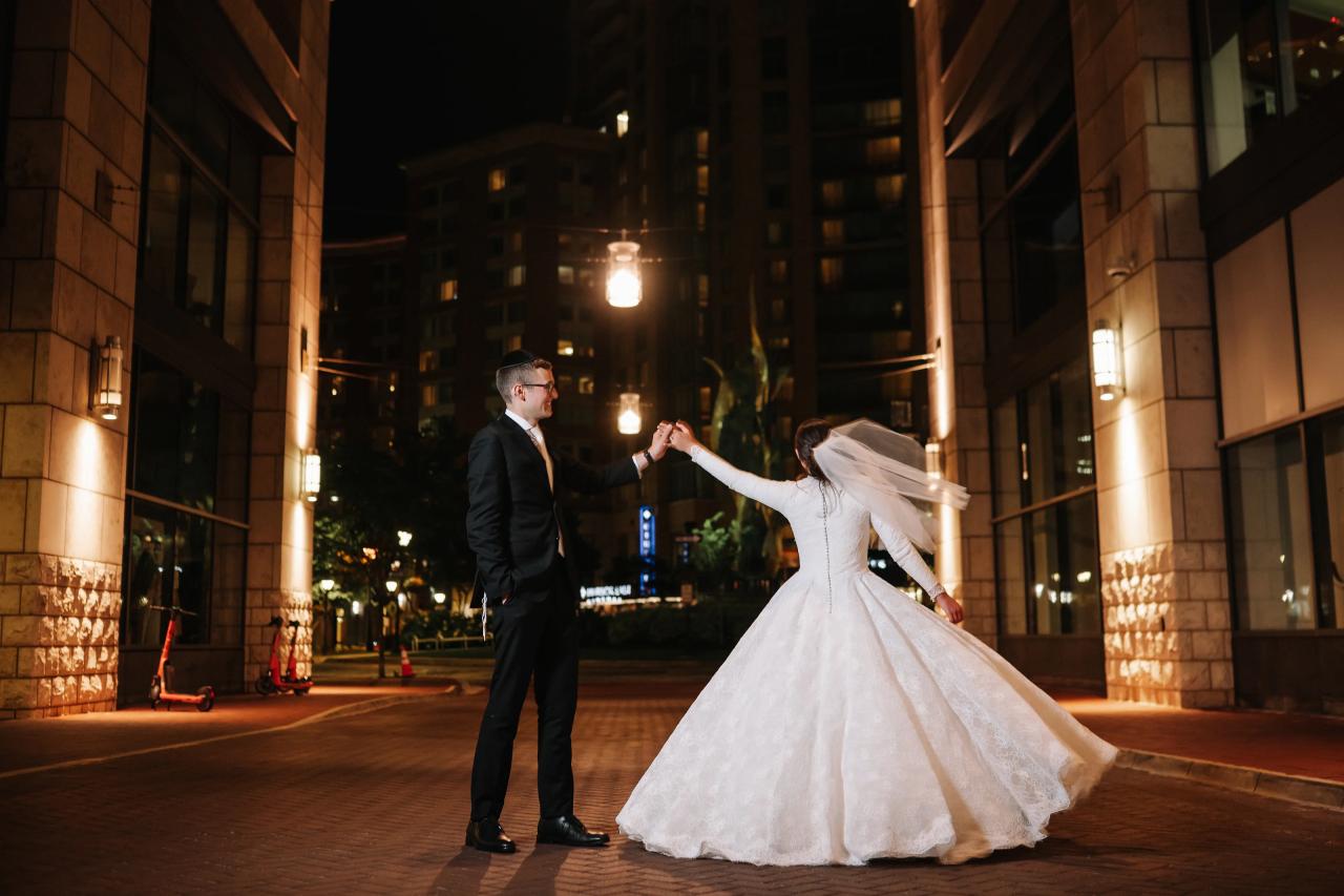 Full-length couple twirl under warm downtown lights; flowing gown and strong architectural framing — couple portraits for the Hilton Baltimore Inner Harbor wedding. Wedding photography.