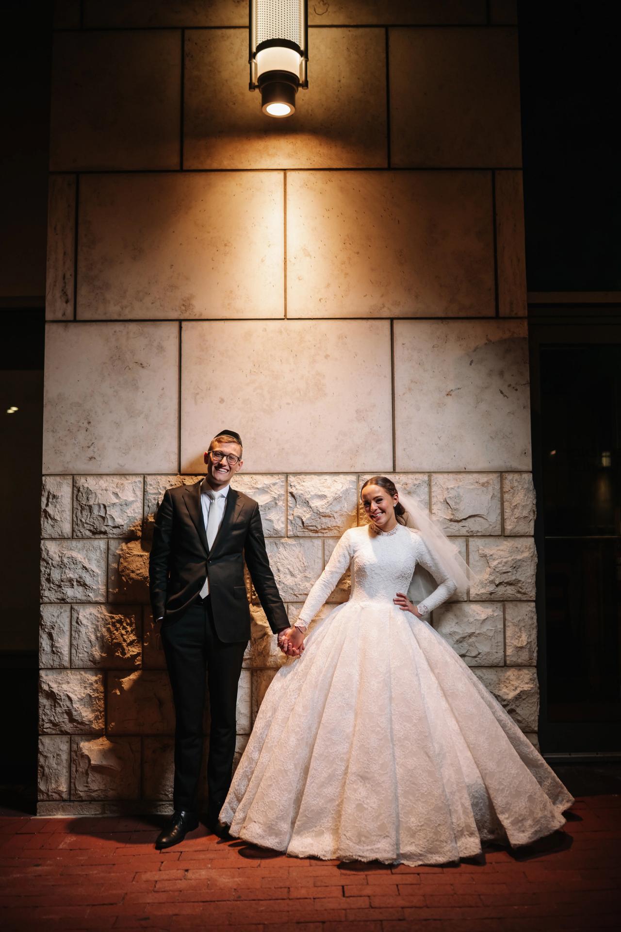 Portrait beneath a single warm wall light; stone textures and the couple’s relaxed posture — couple portraits for the Hilton Baltimore Inner Harbor wedding. Wedding photography.