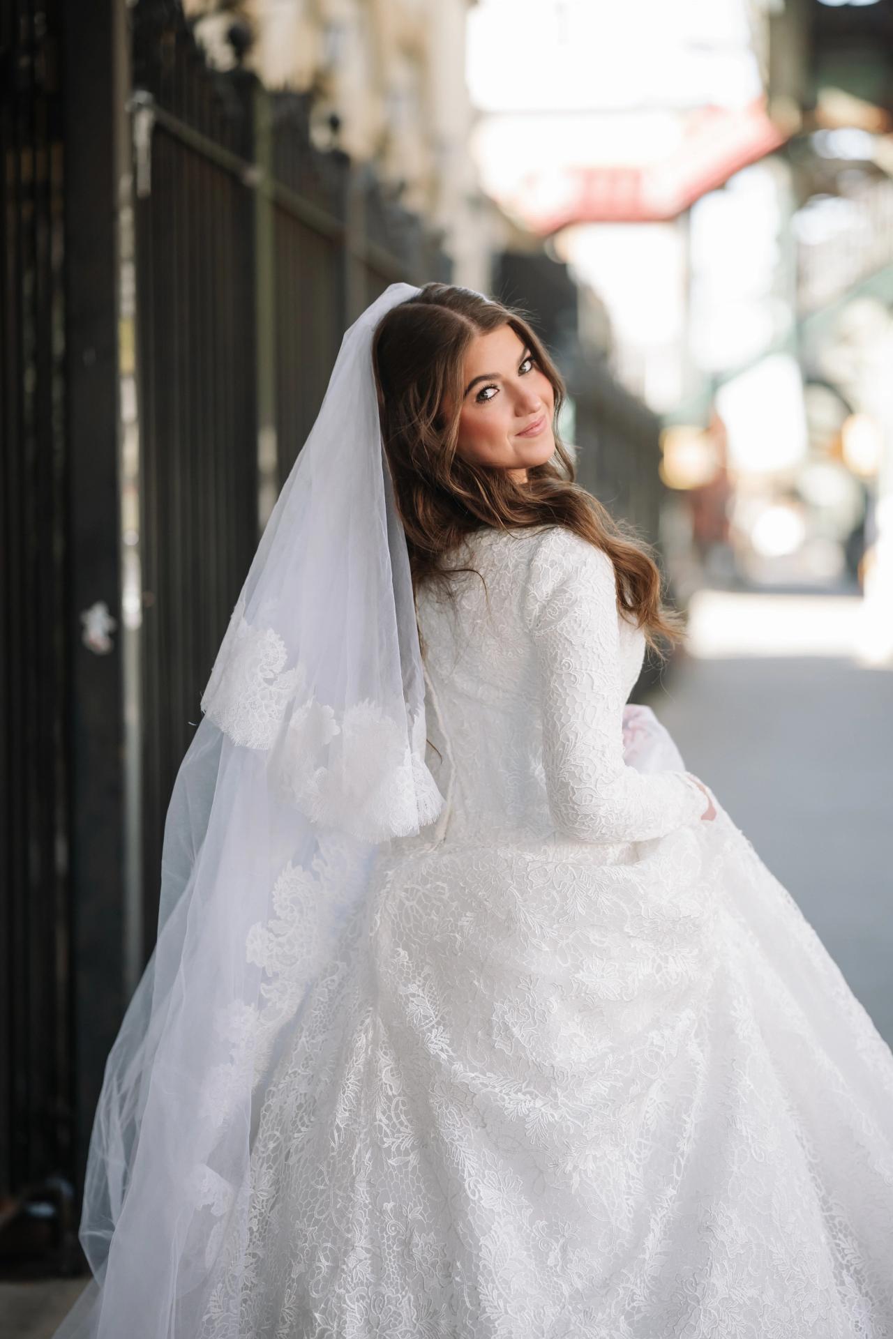 Portrait of the bride in a white lace gown and veil, softly lit in a bright corridor with a blurred architectural background. Wedding photography at The Palace, Brooklyn, NY.