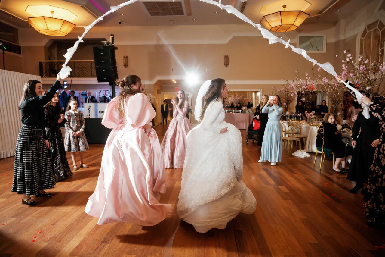 Bride dancing mid-spin on the reception dance floor with warm backlighting and confetti, surrounded by guests. Wedding photography at The Palace, Brooklyn, NY.