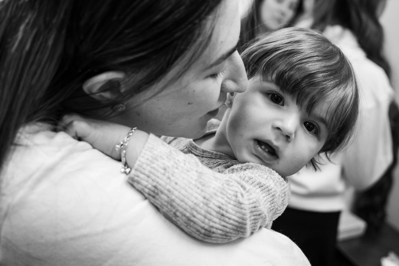 Black-and-white close-up of a woman holding a small child against her shoulder. From this Lake Terrace wedding. Wedding photography.