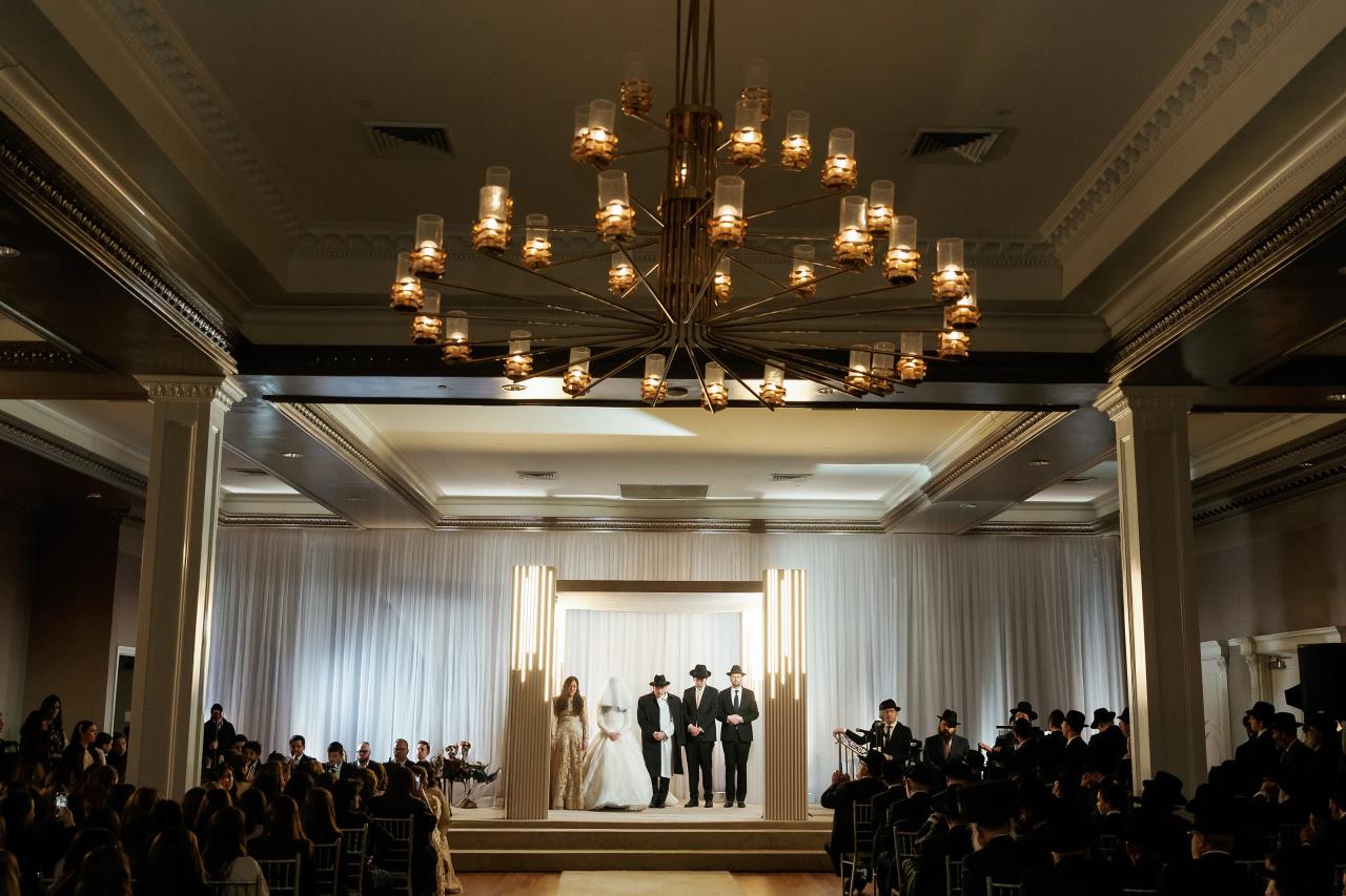 Wide view of the Jewish wedding ceremony beneath a golden chandelier. Wedding photography at Lake Terrace, Lakewood, NJ.