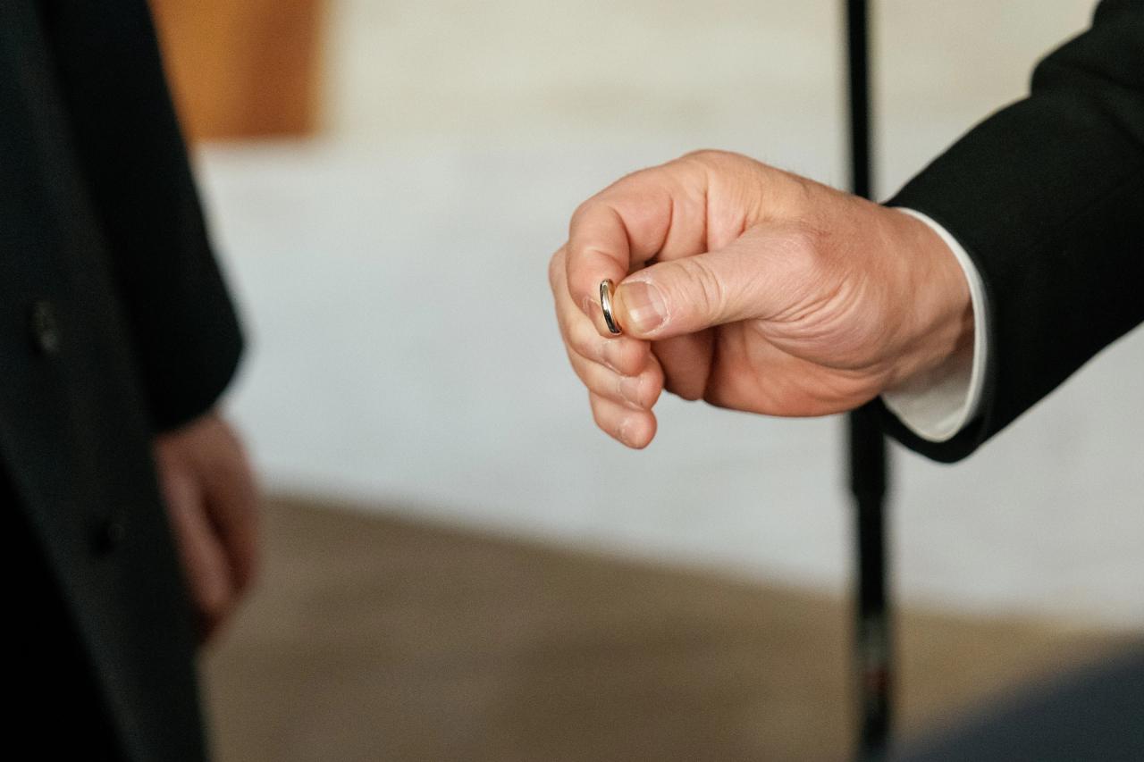 Close-up of a wedding ring held between the fingers. Wedding photography at Lake Terrace, Lakewood, NJ.