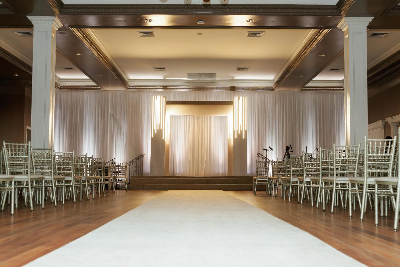 Empty ceremony room with a central aisle, metallic chairs and white drapery. Wedding photography at Lake Terrace, Lakewood, NJ.