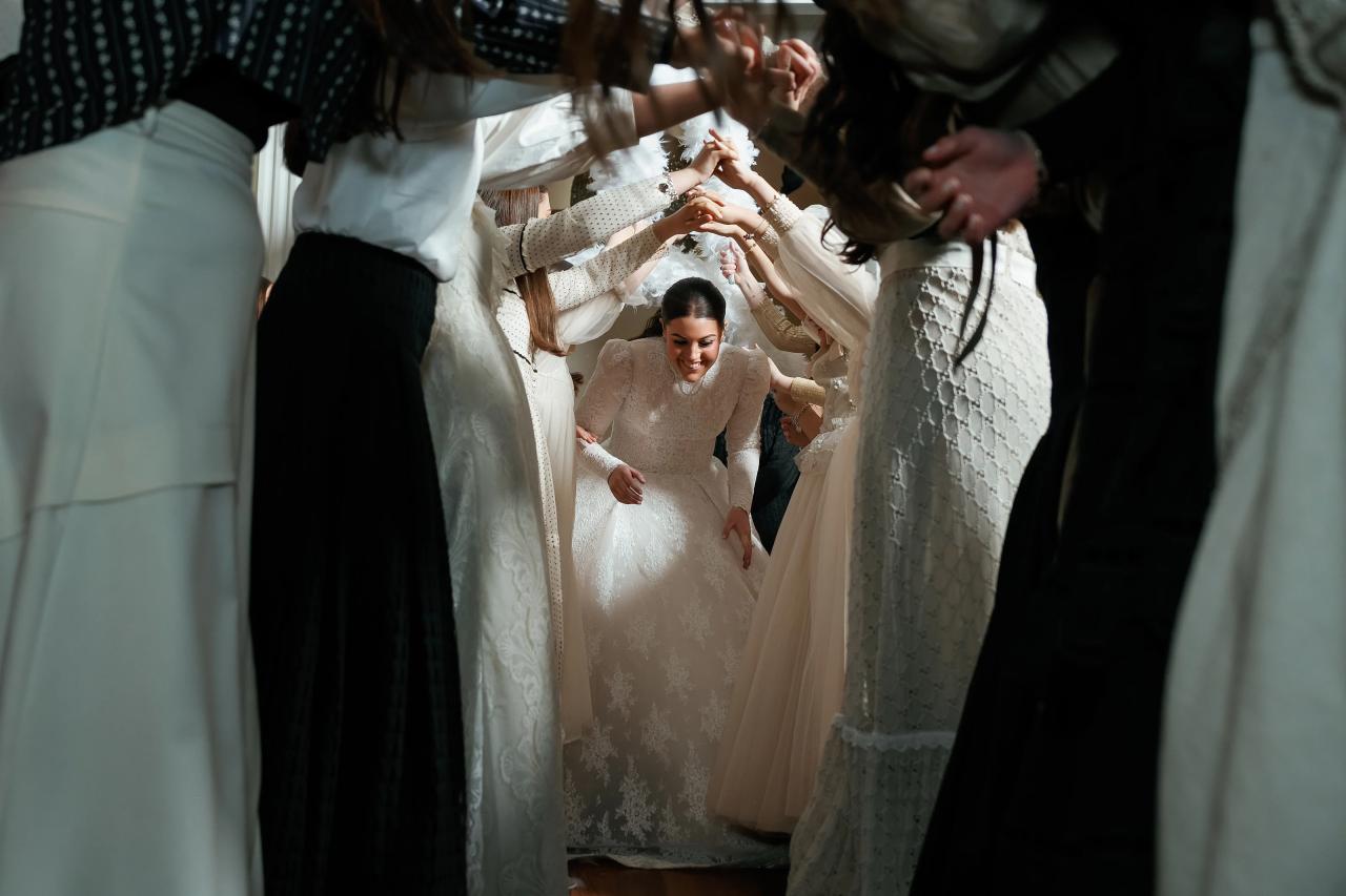 Bride smiling as she ducks beneath a tunnel of raised hands. Wedding photography at Lake Terrace, Lakewood, NJ.