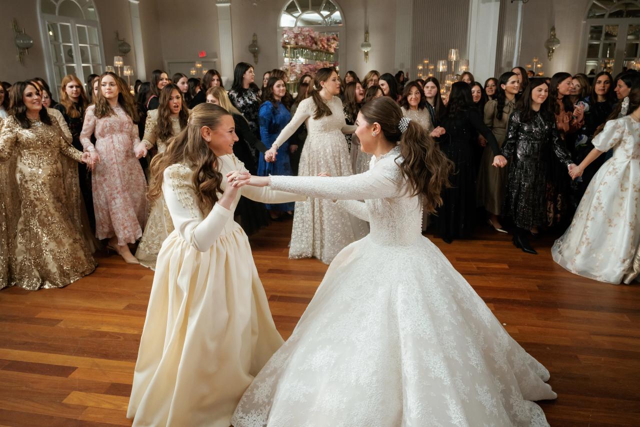 Bride dancing with a young guest while women hold hands behind them. Wedding photography at Lake Terrace, Lakewood, NJ.