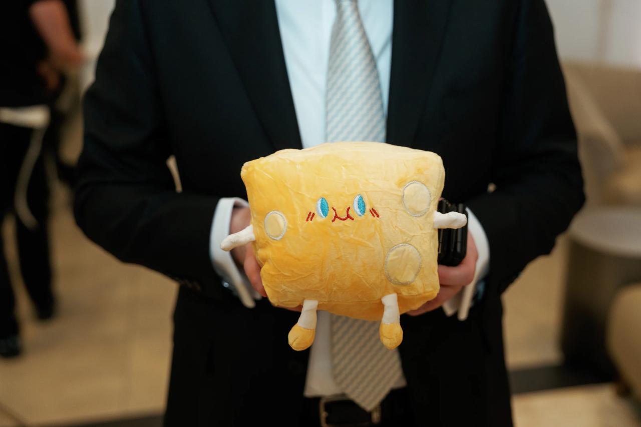 Close-up of a yellow plush toy being held by a man in a suit at a formal celebration, with blurred guests in the background. Wedding photography at Lake Terrace, Lakewood, NJ.