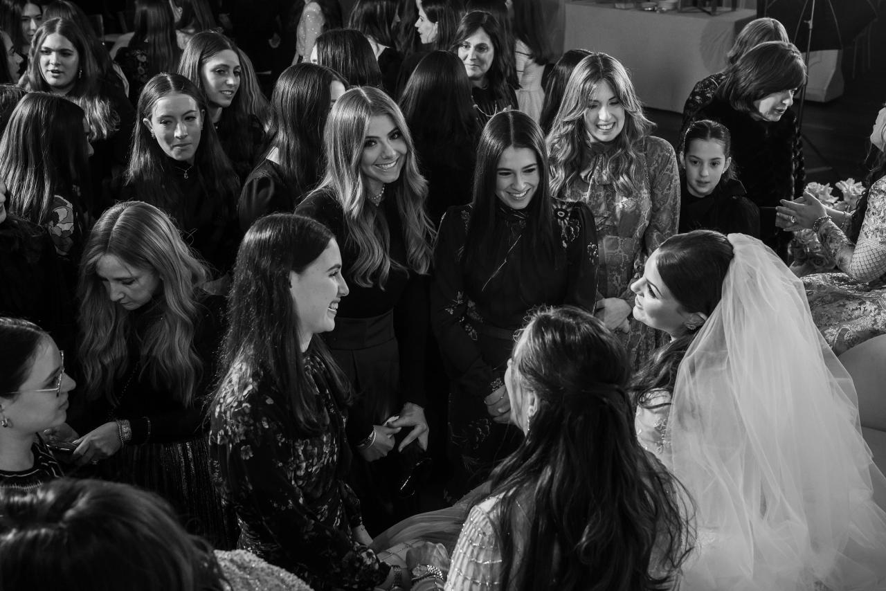 Black-and-white candid of a bride in a veil face-to-face with a nearby guest while guests form a close circle on the dance floor, smiling and watching. Wedding photography at Lake Terrace, Lakewood, NJ.