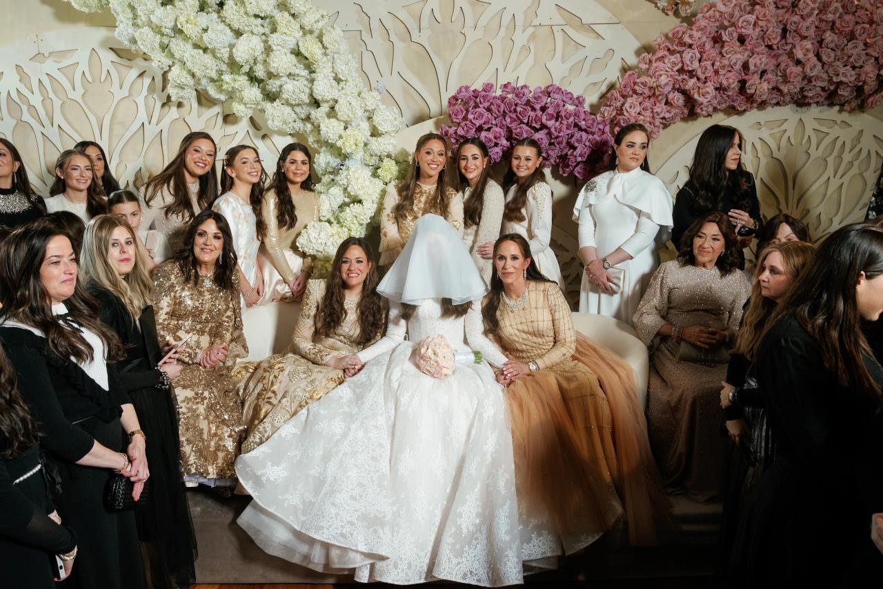 Framed group photo of the bride and groom surrounded by close family and guests in formal attire against an elegant floral backdrop during a Jewish celebration. Wedding photography at Lake Terrace, Lakewood, NJ.